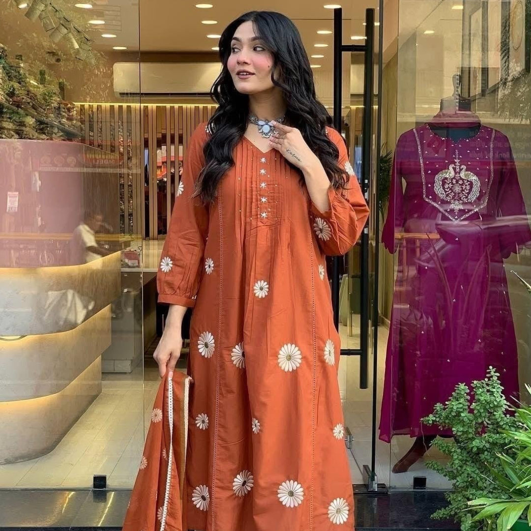 Woman in an orange traditional outfit standing in front of a store window display.