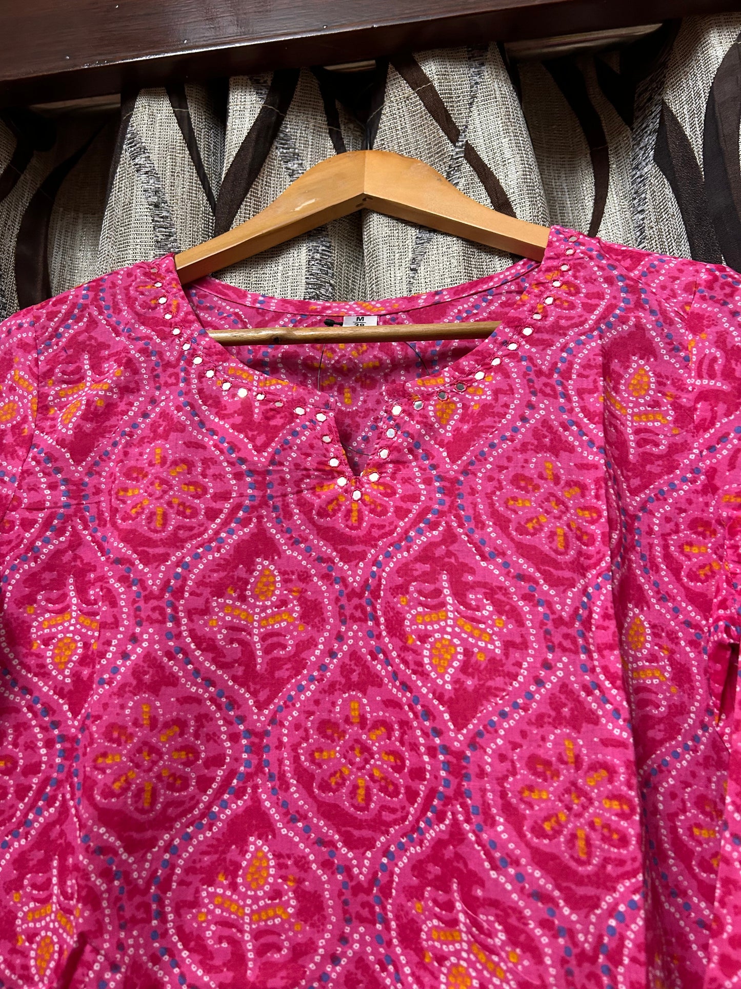 Close-up of mirror work V-notch neckline on rani pink bandhani kurti