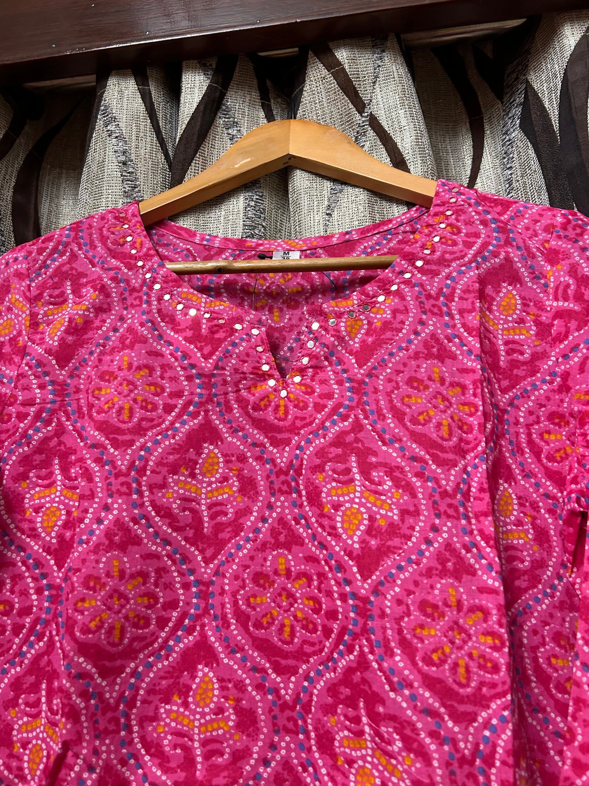 Close-up of mirror work V-notch neckline on rani pink bandhani kurti